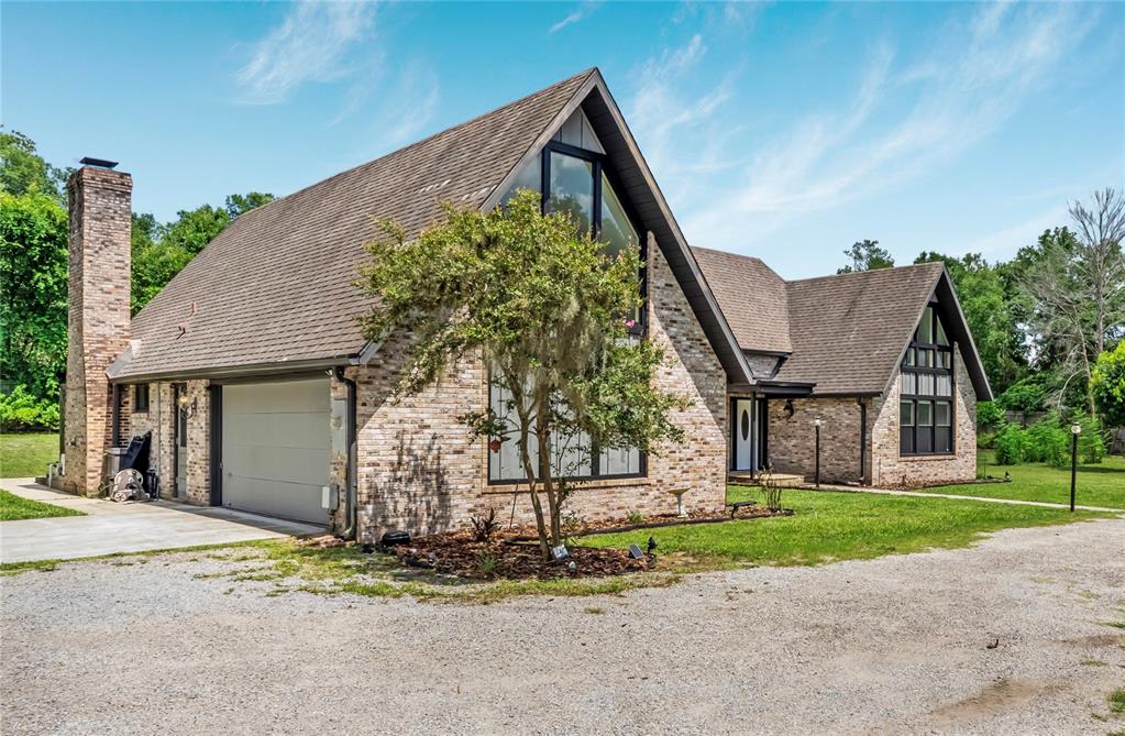 A two-story brick house with a steep roof, large windows, and an attached garage — 1375 LOUIS COURT, DELAND, FL