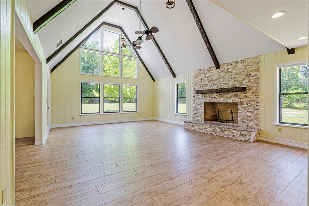 A spacious living room features a vaulted ceiling with exposed beams, stone fireplace, and windows — 1375 LOUIS COURT, DELAND, FL