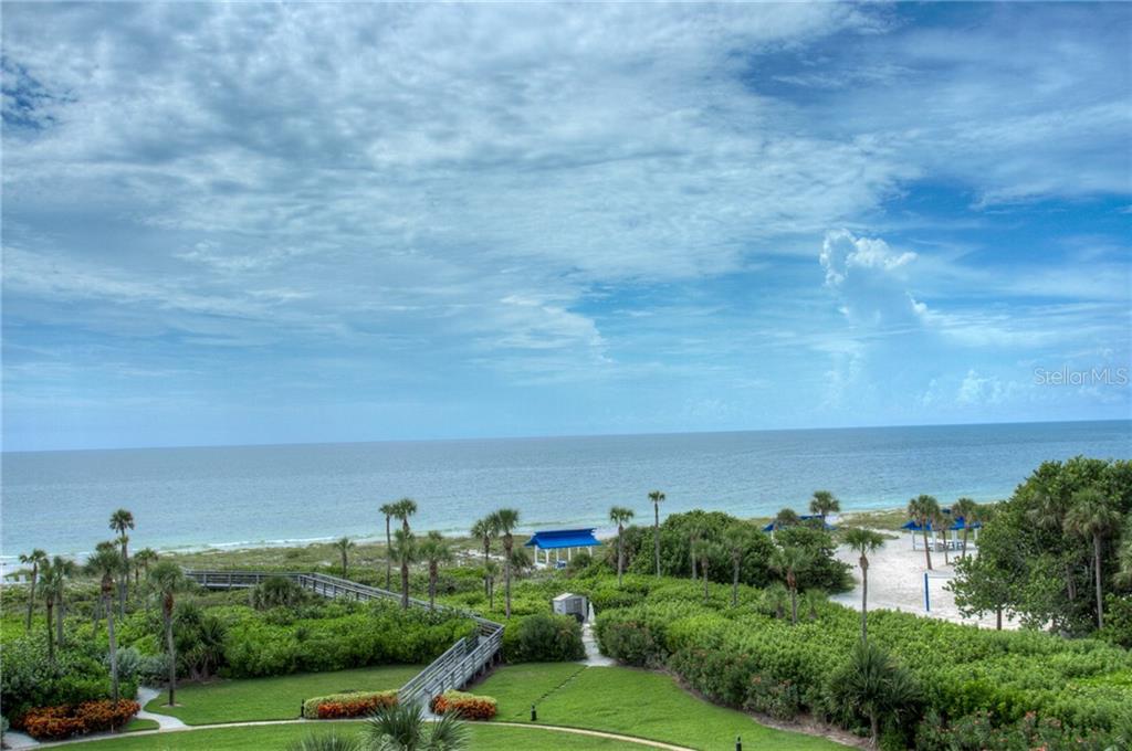 A view of a beach with a wooden walkway, palm trees, and blue sky — 2109 GULF OF MEXICO DRIVE UNIT 1402, LONGBOAT KEY, FL