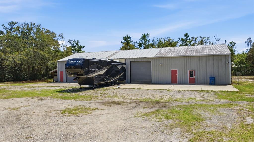 A large metal workshop building with a parked fifth-wheel RV and a gravel yard — 4155 MARSH ROAD, DELAND, FL