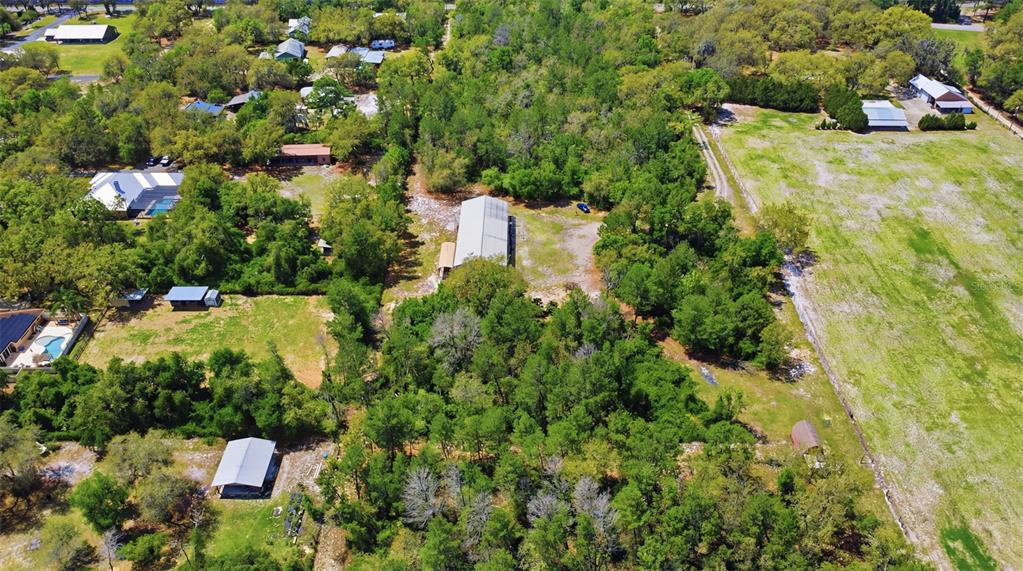 An aerial view shows a rural property with multiple buildings, wooded areas, and open fields — 4155 MARSH ROAD, DELAND, FL