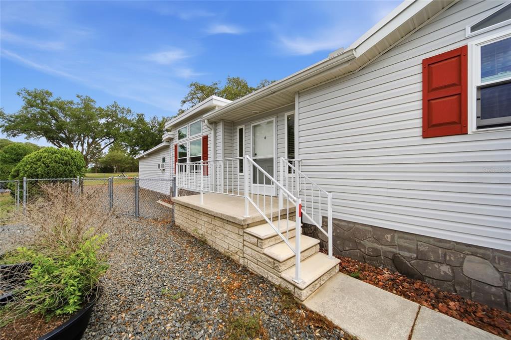 A light gray house exterior features a concrete porch with white railings and stone skirting — 8401 WEATHERFORD AVENUE, BROOKSVILLE, FL