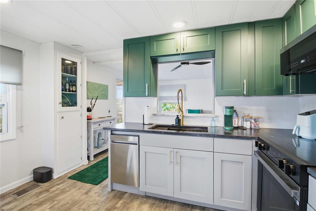 A kitchen features green upper cabinets, light gray lower cabinets, and a dark countertop — 5402 CHATEAU LANE, BRADENTON, FL