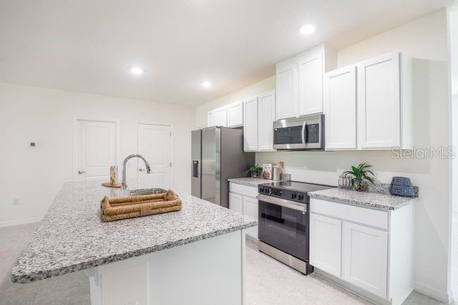 A kitchen with white cabinets, granite countertops, a stainless steel oven, and a center island — 12898 SW 40TH TERRACE, OCALA, FL
