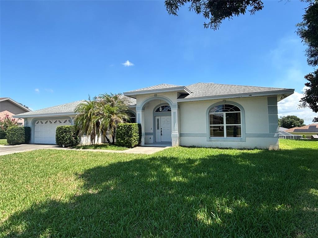 A single-story house with a white stucco exterior, arched entryway, and a two-car garage — 132 LAKE MARIAM WAY, WINTER HAVEN, FL