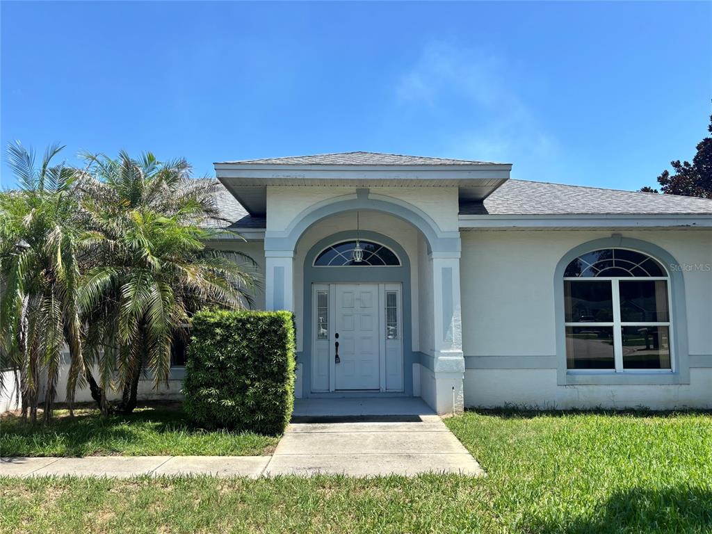 A single-story house with a white stucco facade, arched entryway, and a large front window — 132 LAKE MARIAM WAY, WINTER HAVEN, FL