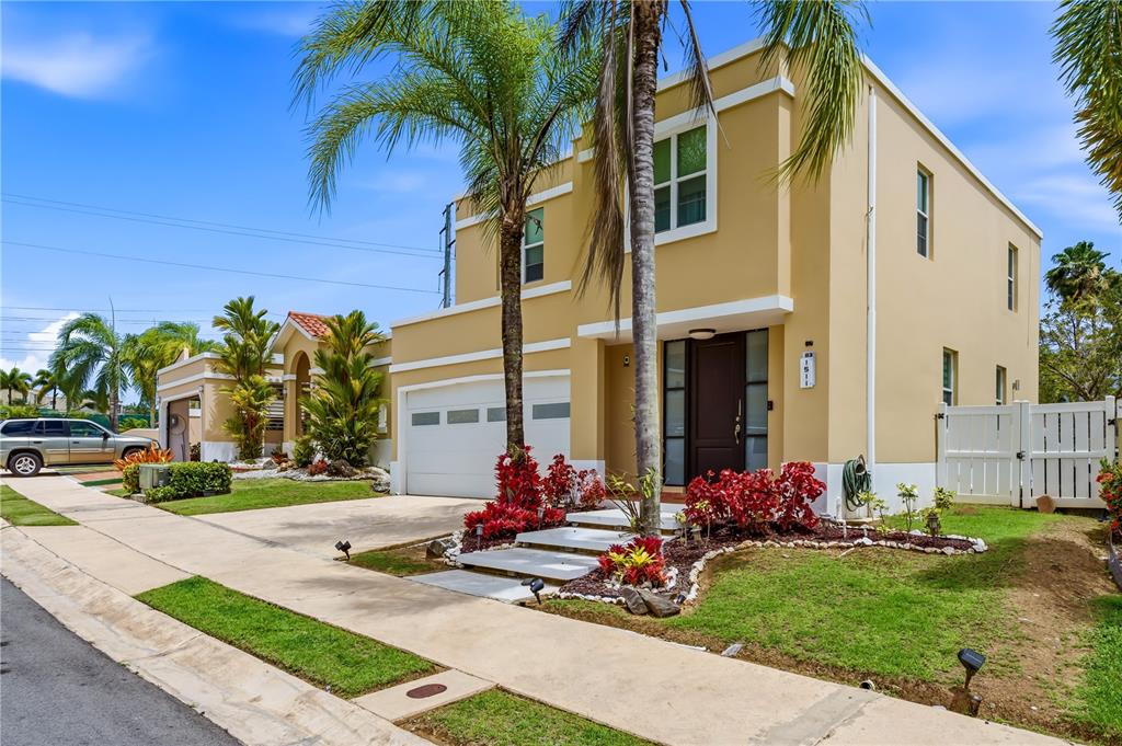 A two-story tan house with a white garage, palm trees, and a landscaped front yard — B-3 EVEREST, TOA ALTA, PR