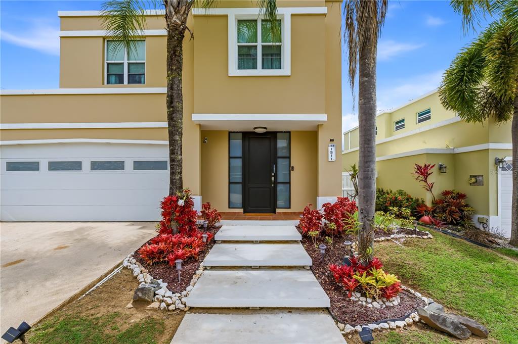 A two-story tan house with a white garage, a dark front door, and palm trees — B-3 EVEREST, TOA ALTA, PR