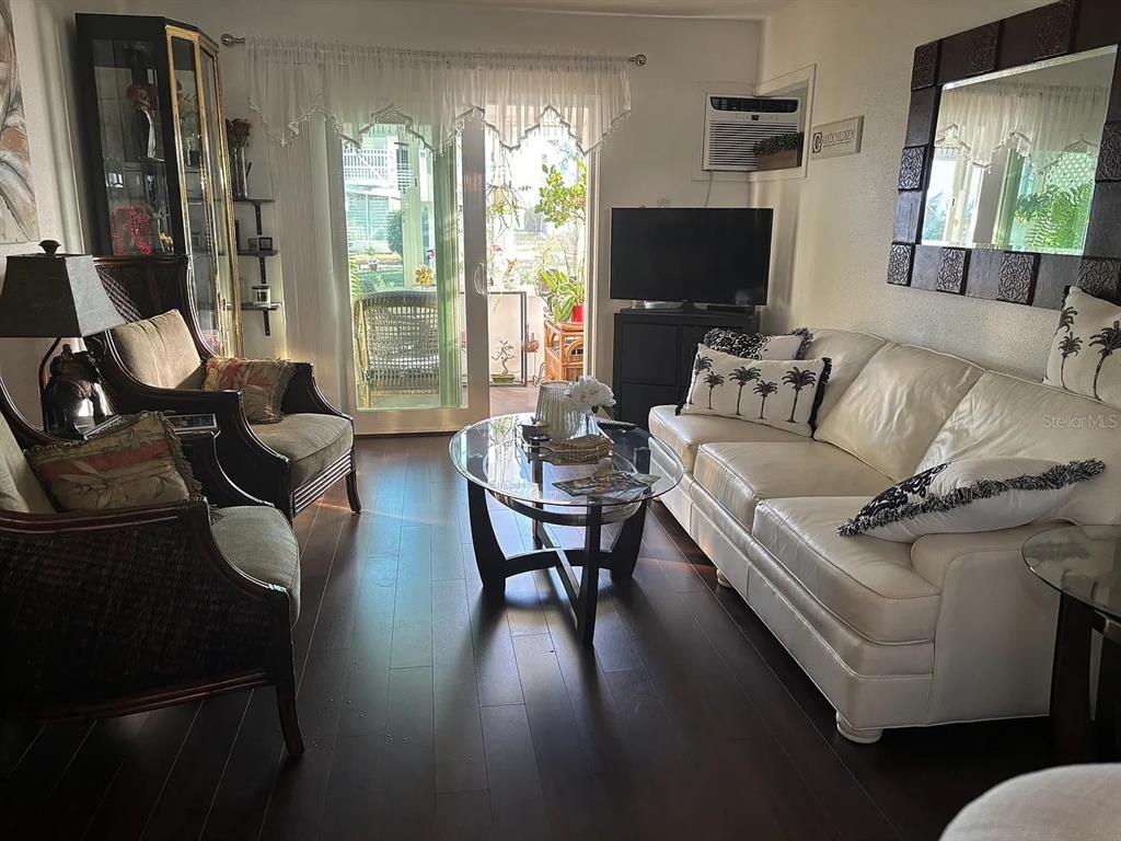 A living room features dark wood flooring, a white sofa, two armchairs, and a glass-topped table — 1605 LEISURE DRIVE UNIT C2, BRADENTON, FL
