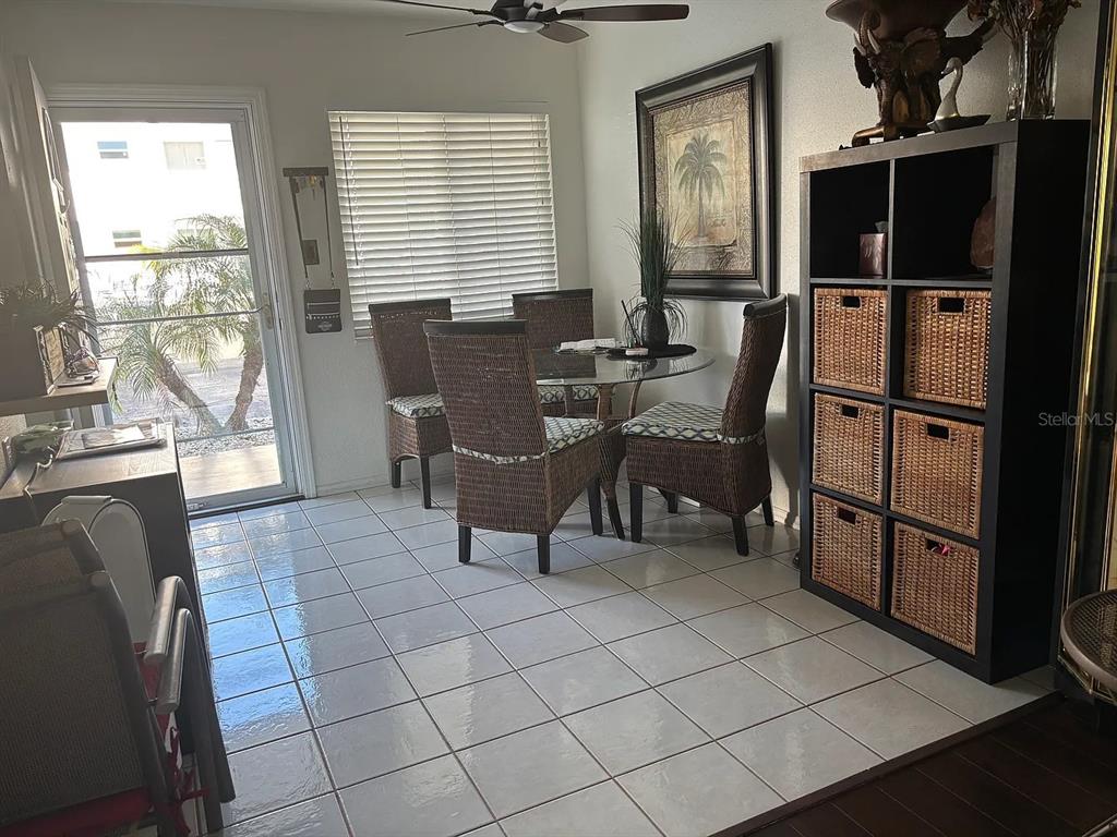 A dining area features a glass table, wicker chairs, tiled floors, and a storage unit — 1605 LEISURE DRIVE UNIT C2, BRADENTON, FL