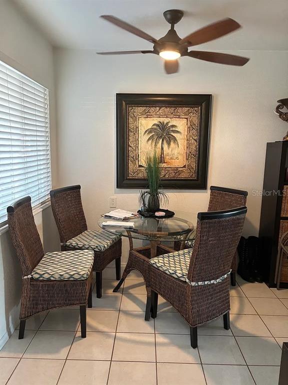 A dining area features a glass-topped table, four wicker chairs, and a ceiling fan — 1605 LEISURE DRIVE UNIT C2, BRADENTON, FL