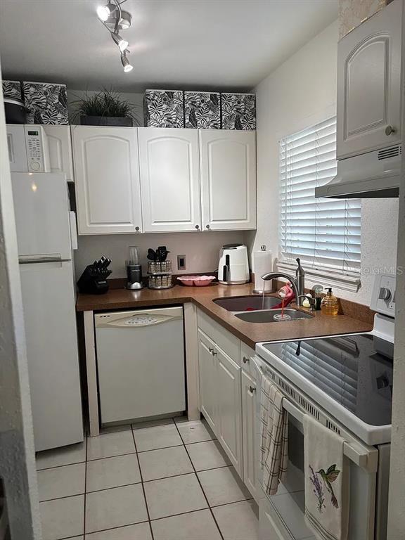 A small kitchen features white cabinets, brown countertops, a white dishwasher, and a white stove — 1605 LEISURE DRIVE UNIT C2, BRADENTON, FL