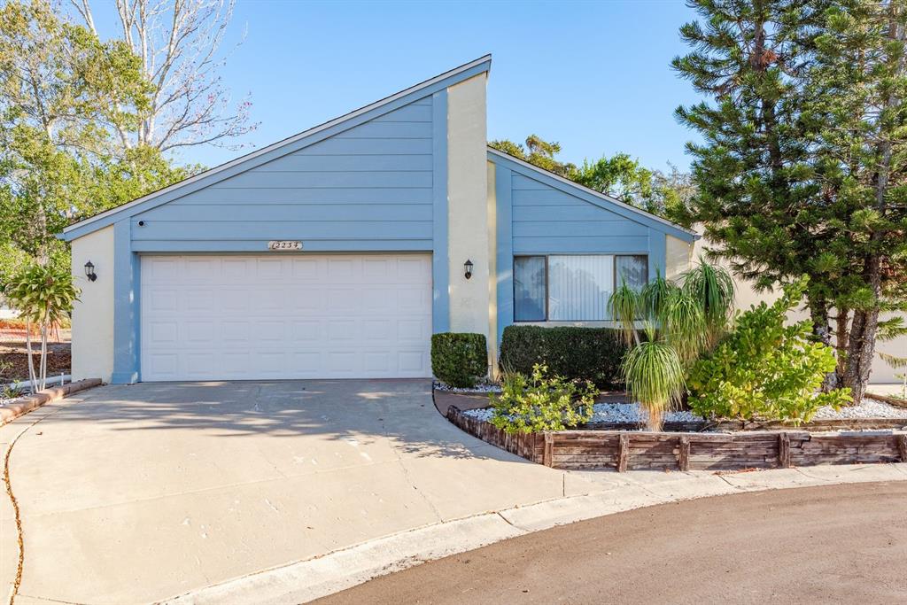 A single-story house with blue siding, a white garage door, and a concrete driveway — 12234 CIDER MILL LANE, HUDSON, FL