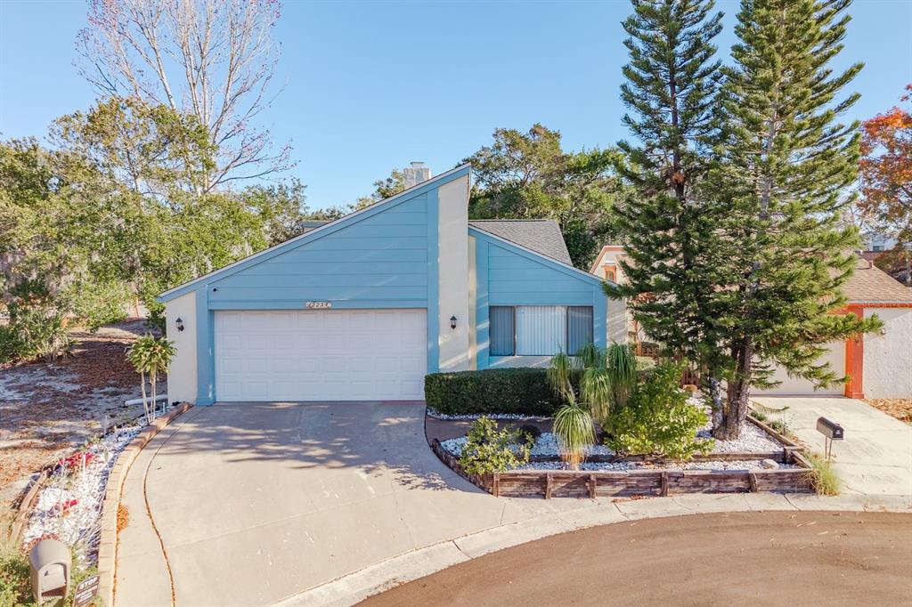 A blue house with a slanted roof, a two-car garage, and a landscaped front yard — 12234 CIDER MILL LANE, HUDSON, FL