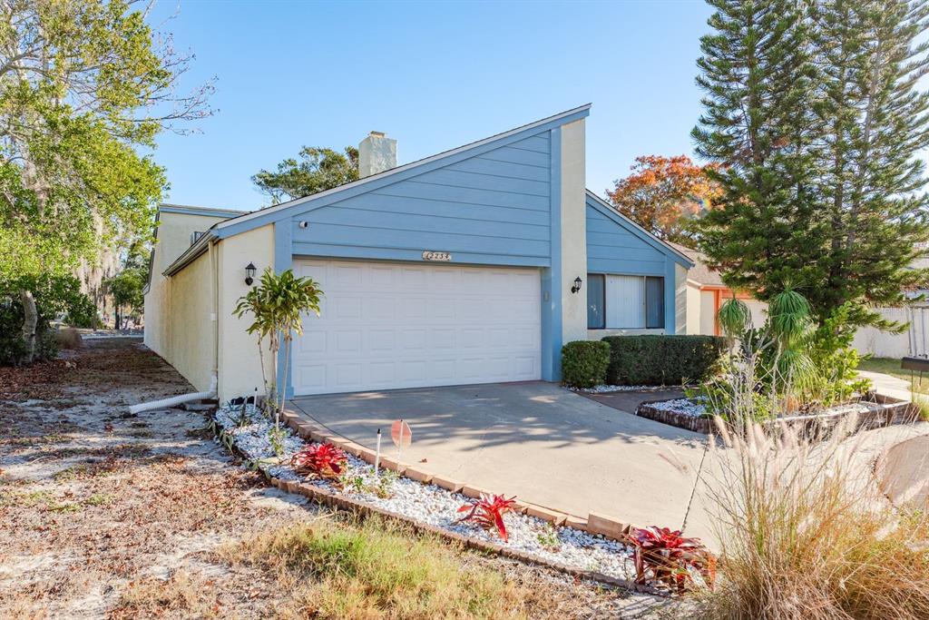 A single-story house with a blue-accented facade, a white garage door, and a concrete driveway — 12234 CIDER MILL LANE, HUDSON, FL