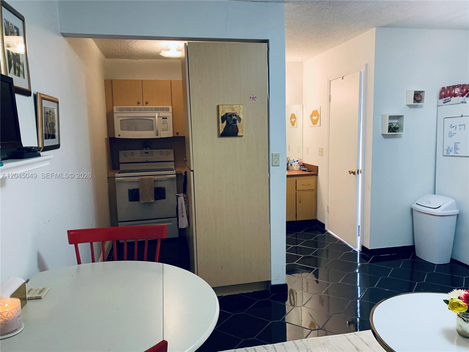 A kitchen with light wood cabinets and a bathroom area with black tile flooring — 11230 SW 138th St # A, Miami FL 33176, MIAMI, FL