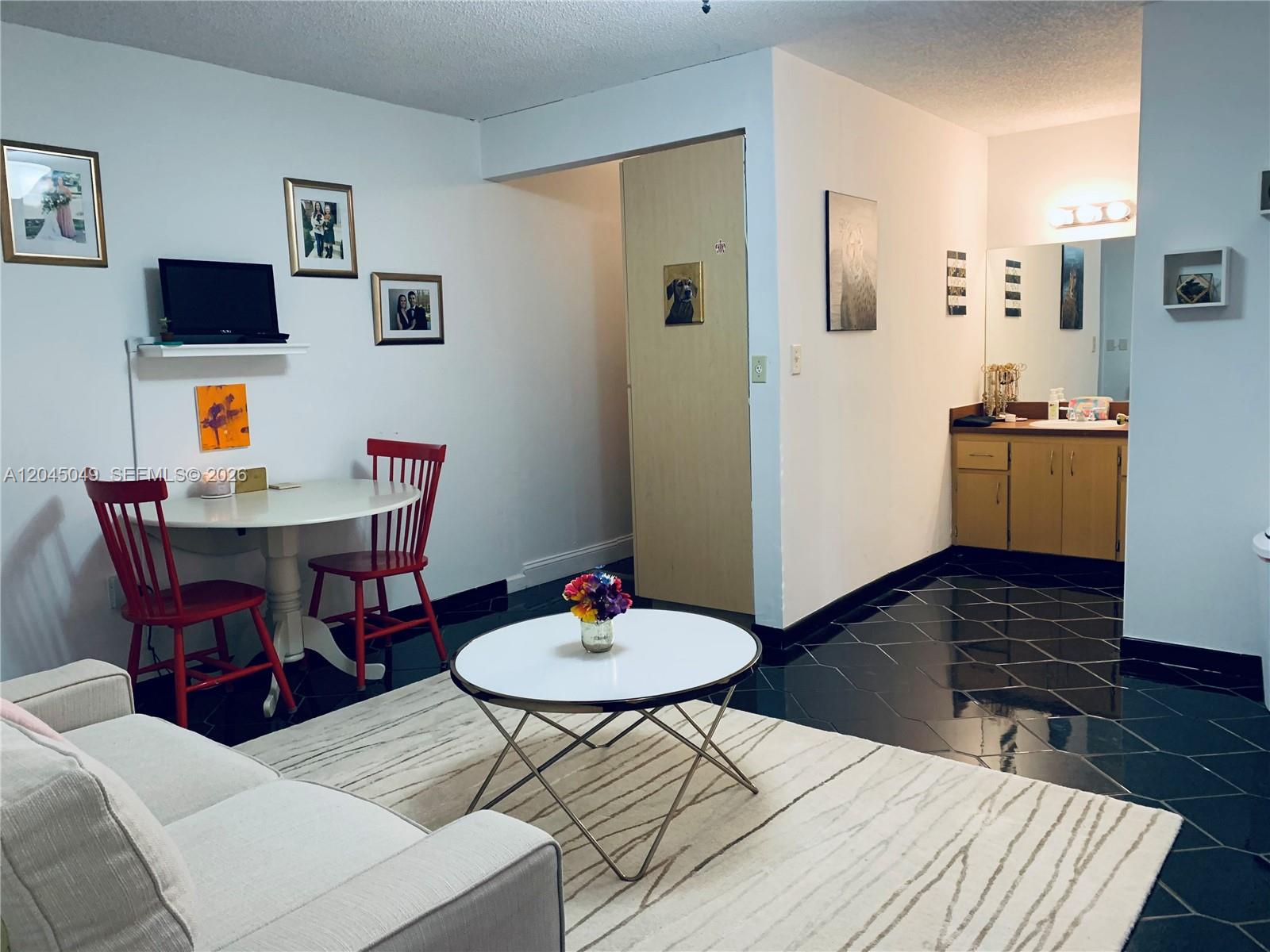 A living area with a dining table, sofa, and an adjacent vanity with black tile — 11230 SW 138th St # A, Miami FL 33176, MIAMI, FL