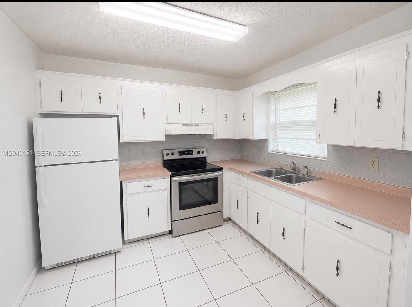 A kitchen with white cabinets, pink laminate countertops, stainless steel appliances, and white tile flooring — 5771 SW 36th Ct # 301, Davie FL 33314, DAVIE, FL