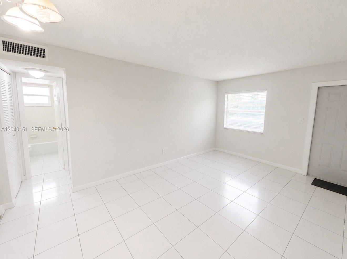 A bright room with white tile flooring, a window, and an adjacent bathroom doorway — 5771 SW 36th Ct # 301, Davie FL 33314, DAVIE, FL