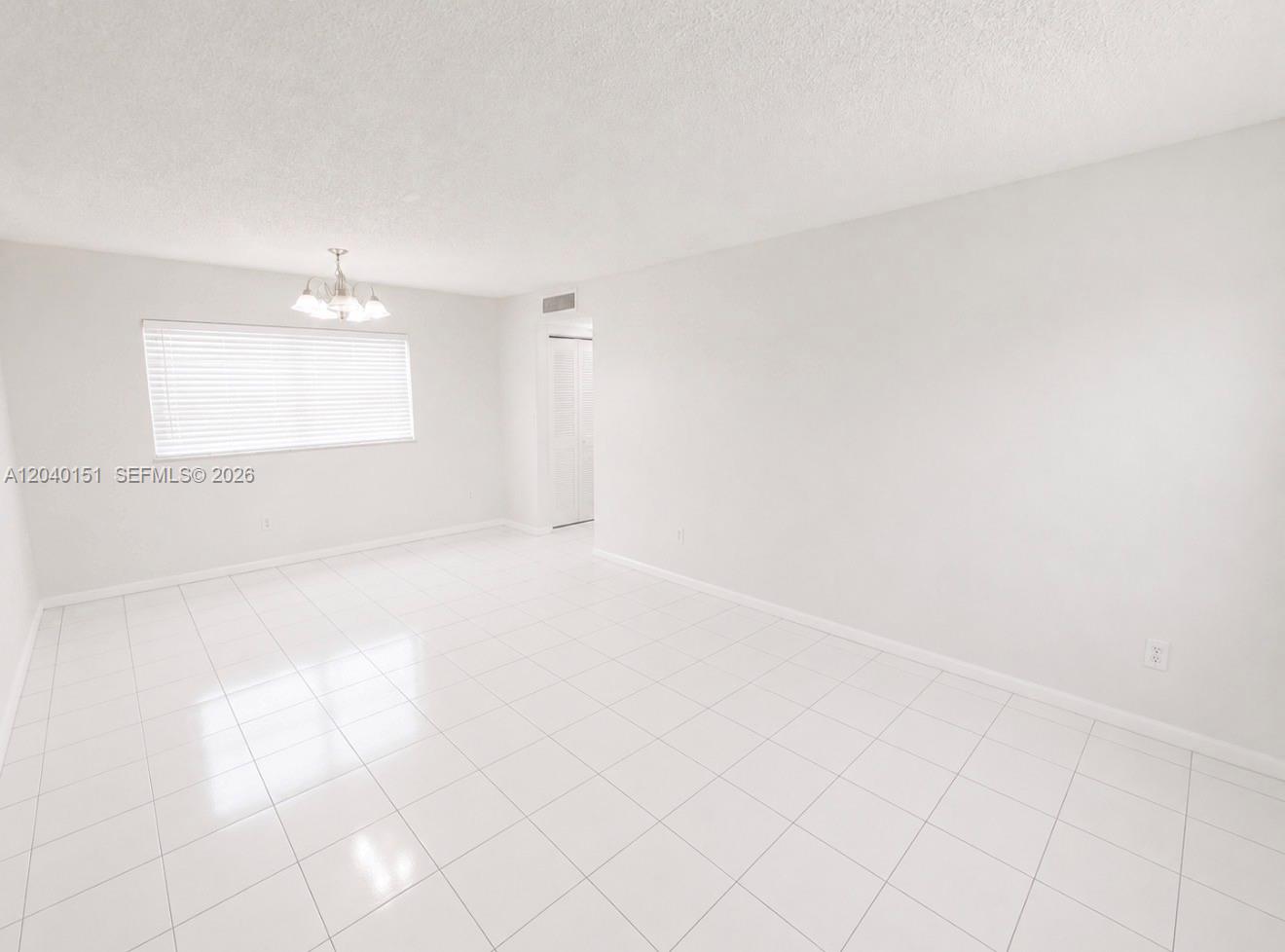 A bright, empty room features white walls, white tile flooring, and a hanging light fixture — 5771 SW 36th Ct # 301, Davie FL 33314, DAVIE, FL