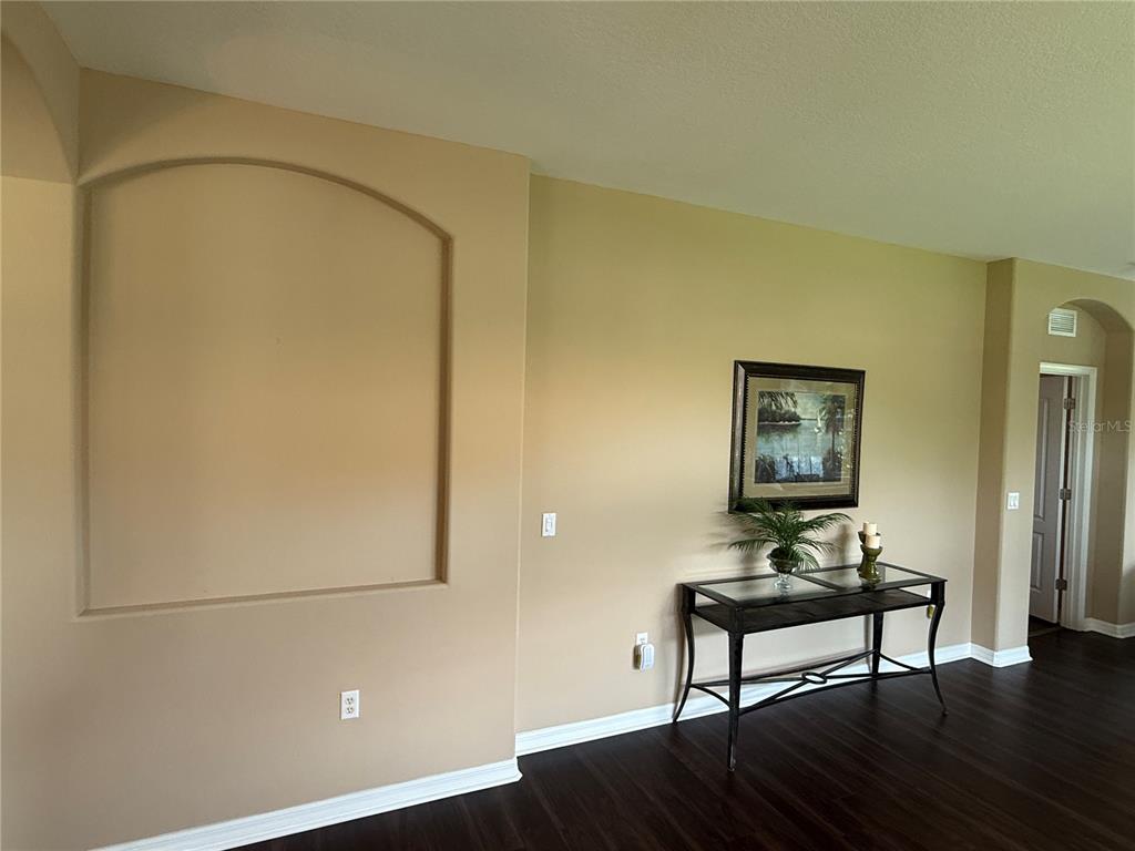 A room with dark wood flooring, a recessed arched wall niche, and a console table — 5064 WHISPERING OAKS DRIVE, NORTH PORT, FL