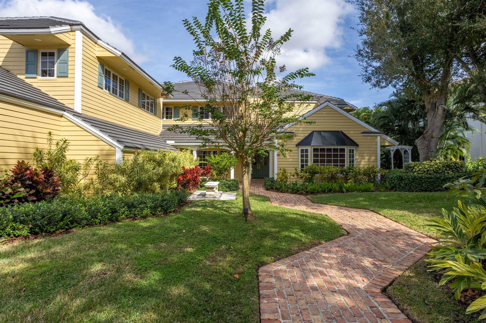 A yellow two-story house with a brick walkway leading to the front entrance — 2883 Banyan Boulevard Circle NW, Boca Raton FL 33431, BOCA RATON, FL