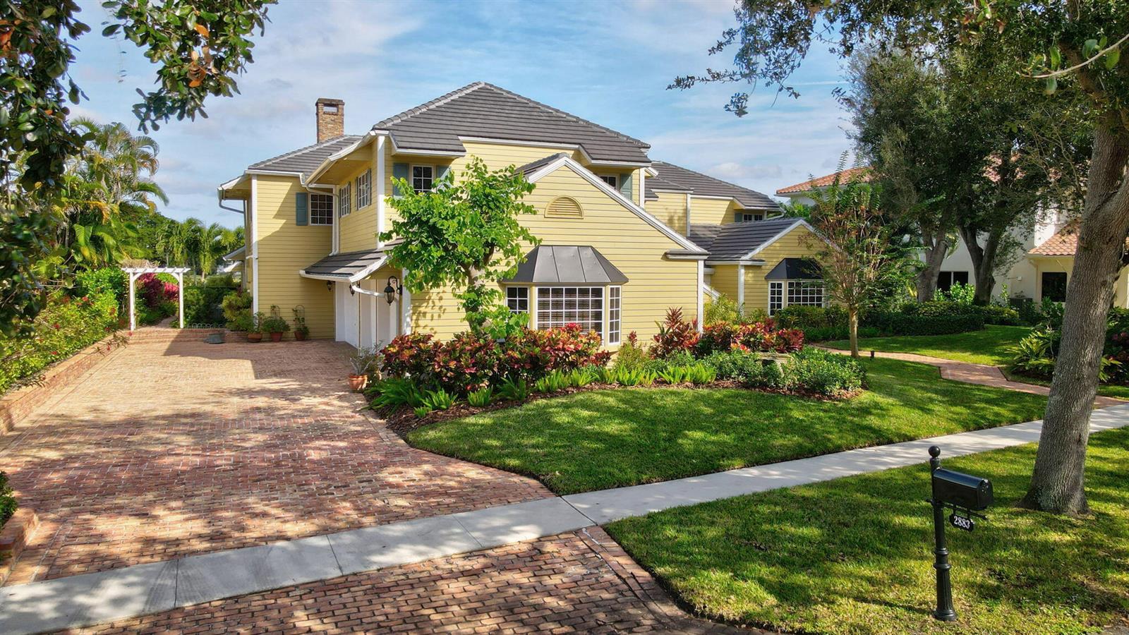 A two-story yellow house with a brick driveway and a dark shingled roof — 2883 Banyan Boulevard Circle NW, Boca Raton FL 33431, BOCA RATON, FL