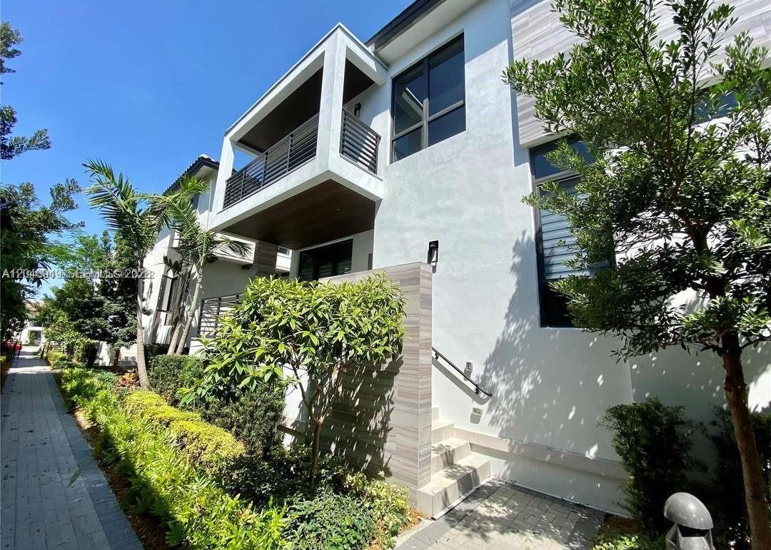 A modern two-story townhouse exterior features a balcony, stone-accented wall, and a paved walkway — 8256 NW 48th ter, Doral FL 33166, DORAL, FL