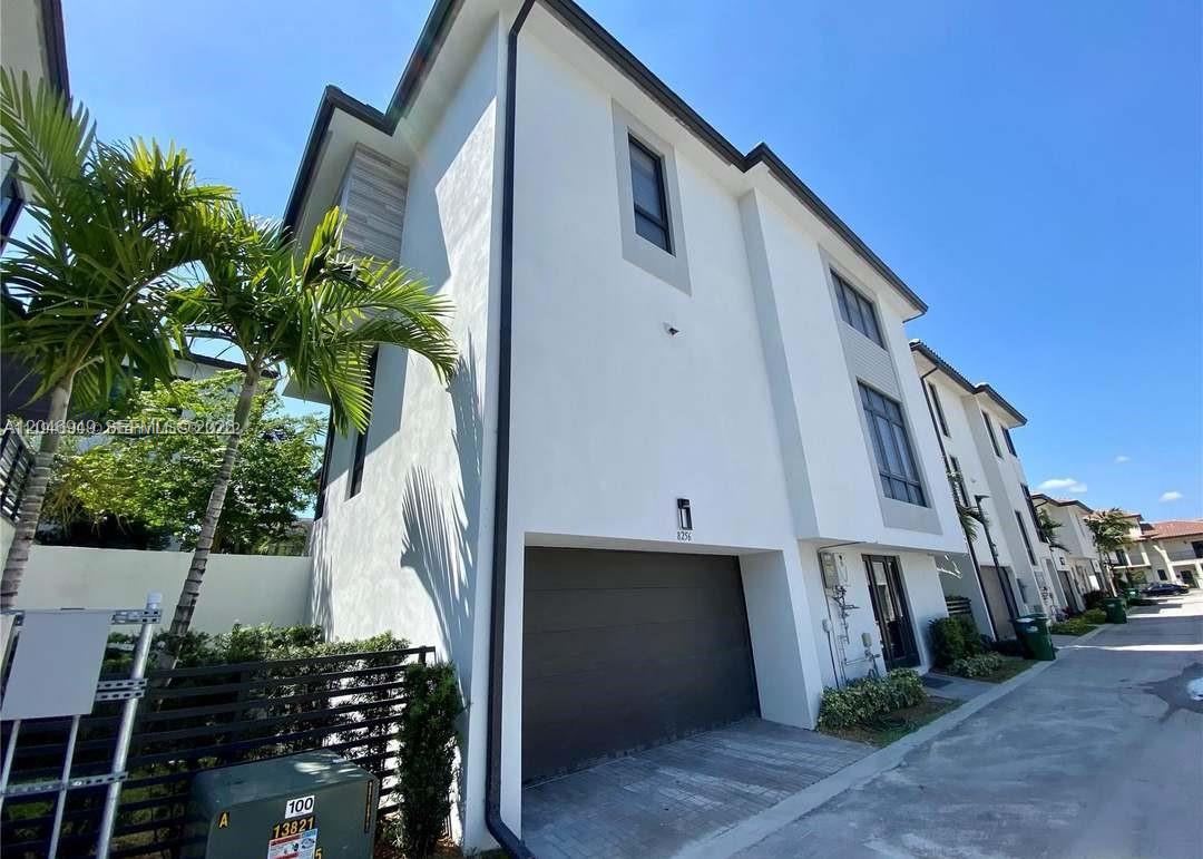 A modern white multi-story townhouse features a dark garage door and a palm tree — 8256 NW 48th ter, Doral FL 33166, DORAL, FL