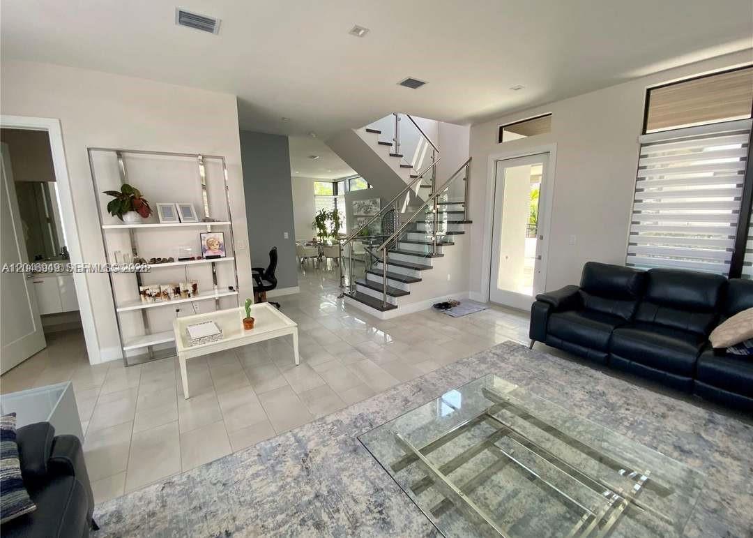 A modern living room features a glass staircase, white tile floors, and a black leather sofa — 8256 NW 48th ter, Doral FL 33166, DORAL, FL