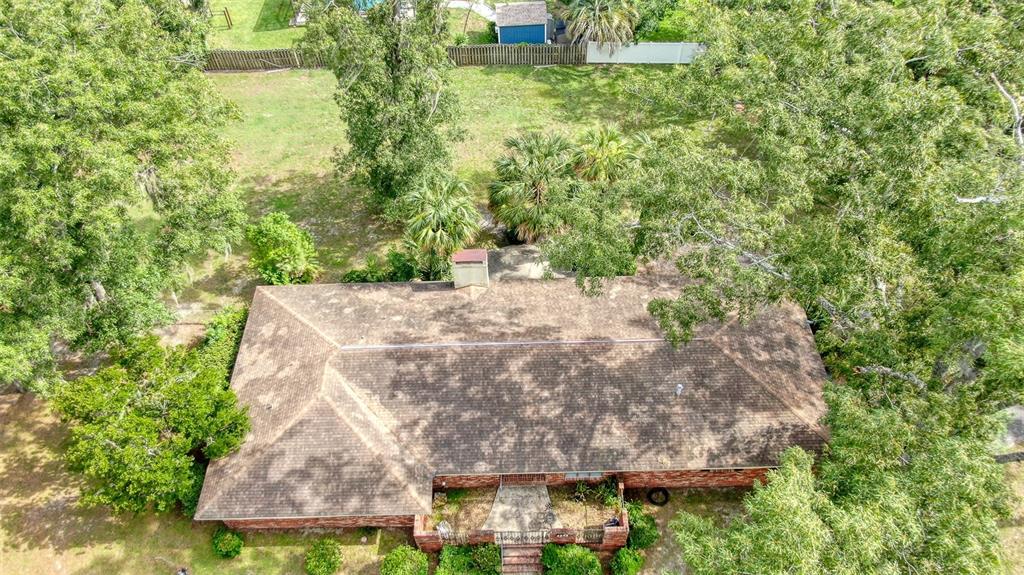 An aerial view shows a brick house with a shingled roof surrounded by large trees — 4243 SE 8TH STREET, OCALA, FL