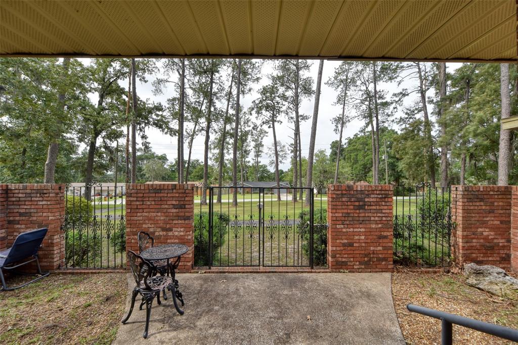 A covered brick patio features a small metal bistro set and a wrought iron gate — 4243 SE 8TH STREET, OCALA, FL