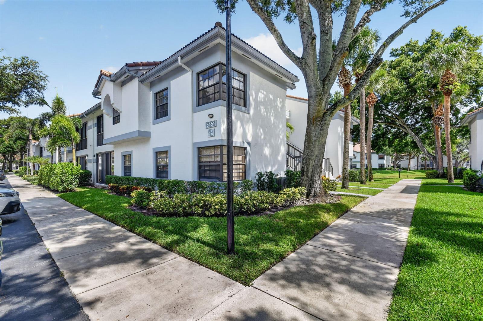 A two-story white apartment building with gray trim sits next to a sidewalk and trees — 5451 Verona Drive, Boynton Beach FL 33437, BOYNTON BEACH, FL