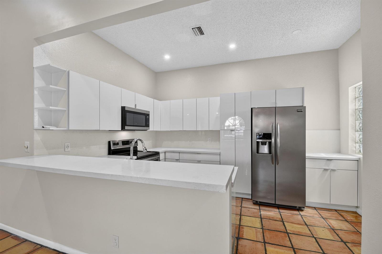 A kitchen with white cabinets, stainless steel appliances, a breakfast bar, and terracotta tile flooring — 5451 Verona Drive, Boynton Beach FL 33437, BOYNTON BEACH, FL