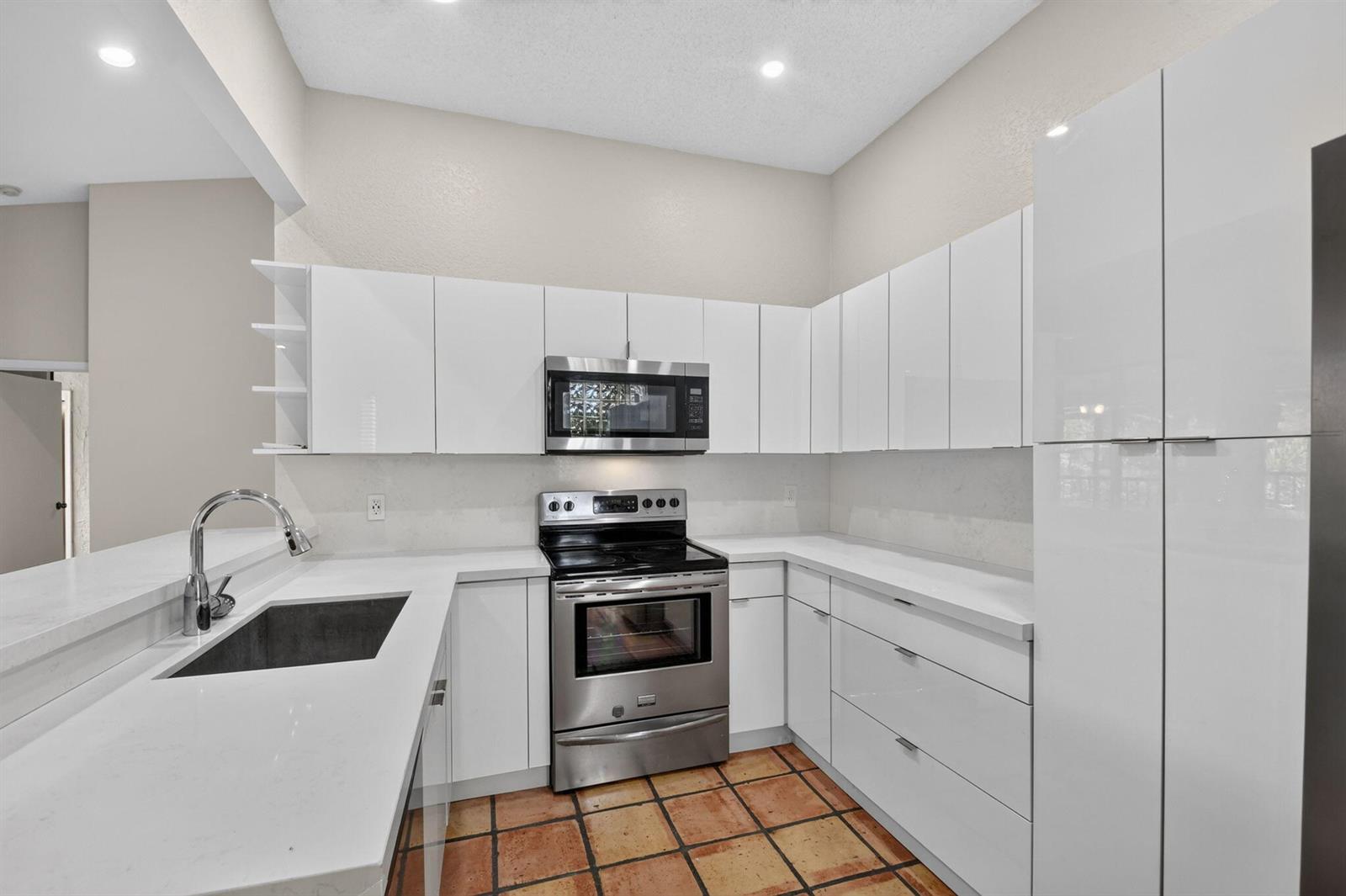 A kitchen with white flat-panel cabinets, stainless steel appliances, white countertops, and terracotta tile flooring — 5451 Verona Drive, Boynton Beach FL 33437, BOYNTON BEACH, FL