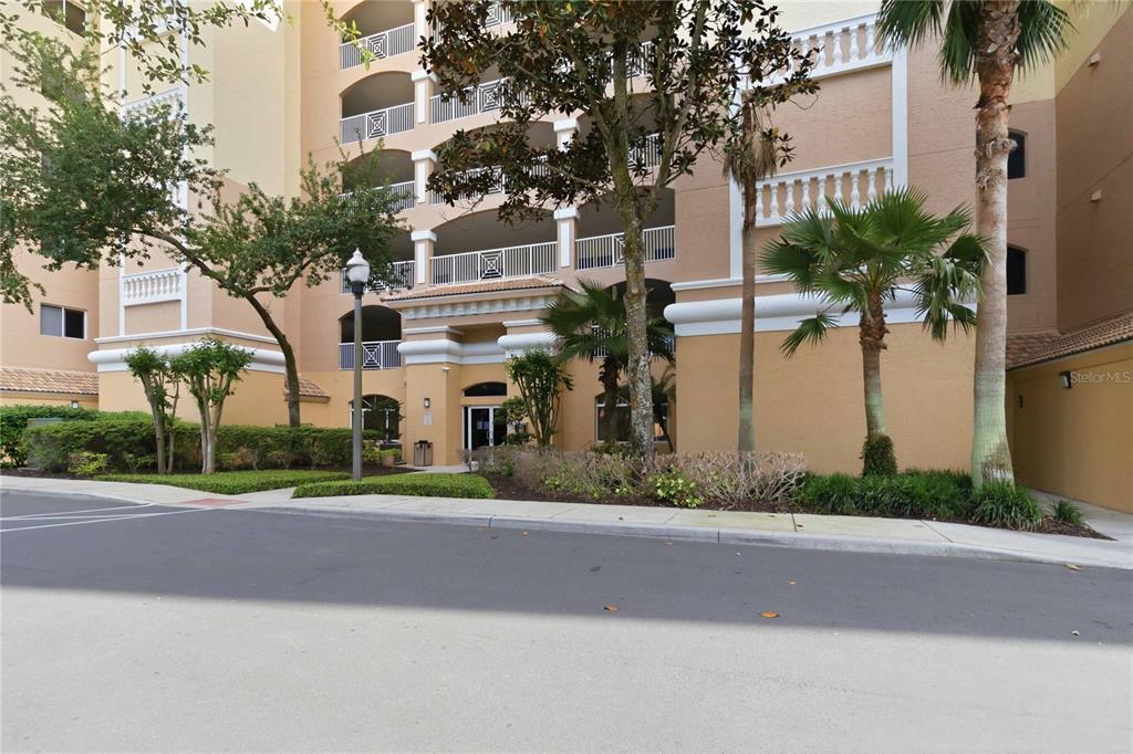 The exterior of a multi-story tan apartment building features balconies and palm trees — 6336 BUFORD STREET UNIT 209, ORLANDO, FL