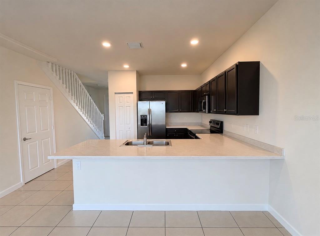 A kitchen features dark wood cabinets, stainless steel appliances, and a light-colored breakfast bar — 11553 SW 248TH TERRACE, HOMESTEAD, FL