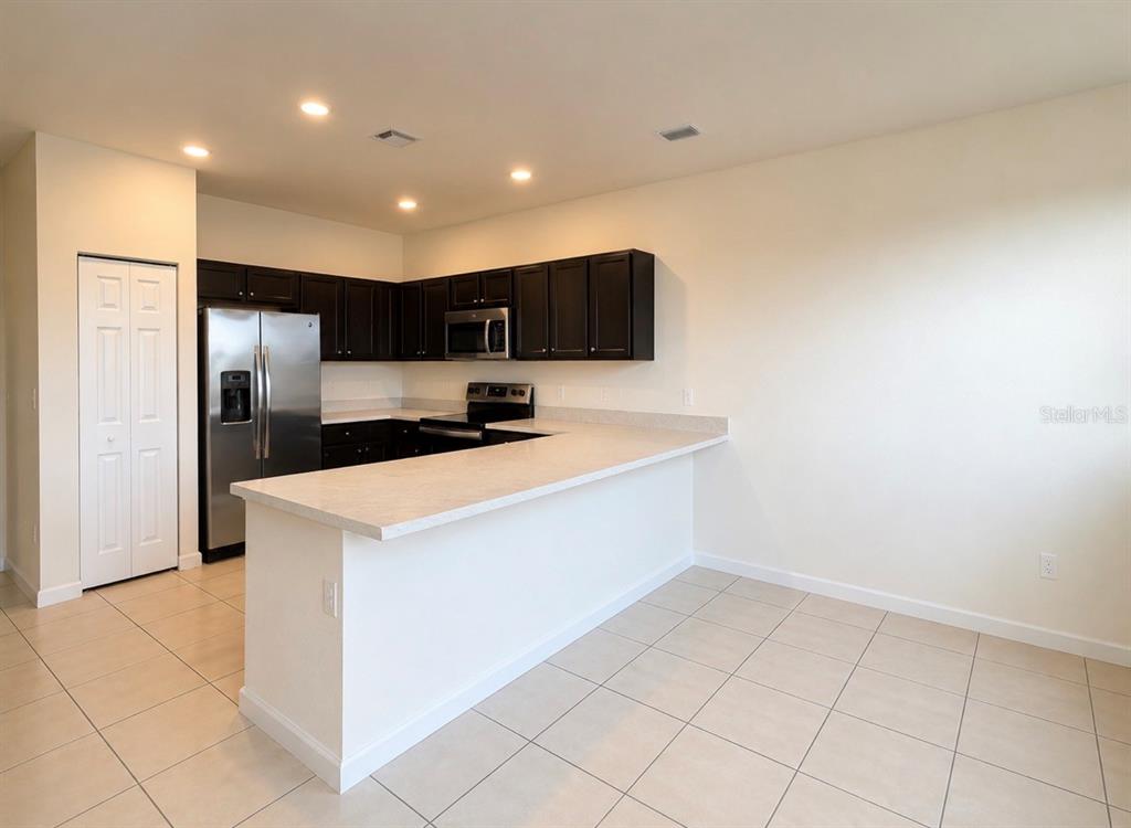 A kitchen features dark cabinets, stainless steel appliances, and a white breakfast bar — 11553 SW 248TH TERRACE, HOMESTEAD, FL