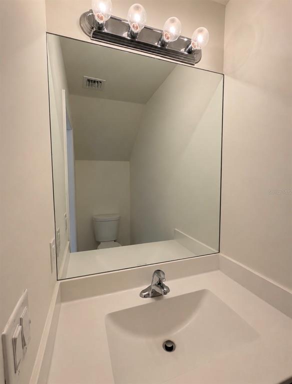 A bathroom vanity with a white countertop, chrome faucet, large mirror, and four-bulb light fixture — 11553 SW 248TH TERRACE, HOMESTEAD, FL
