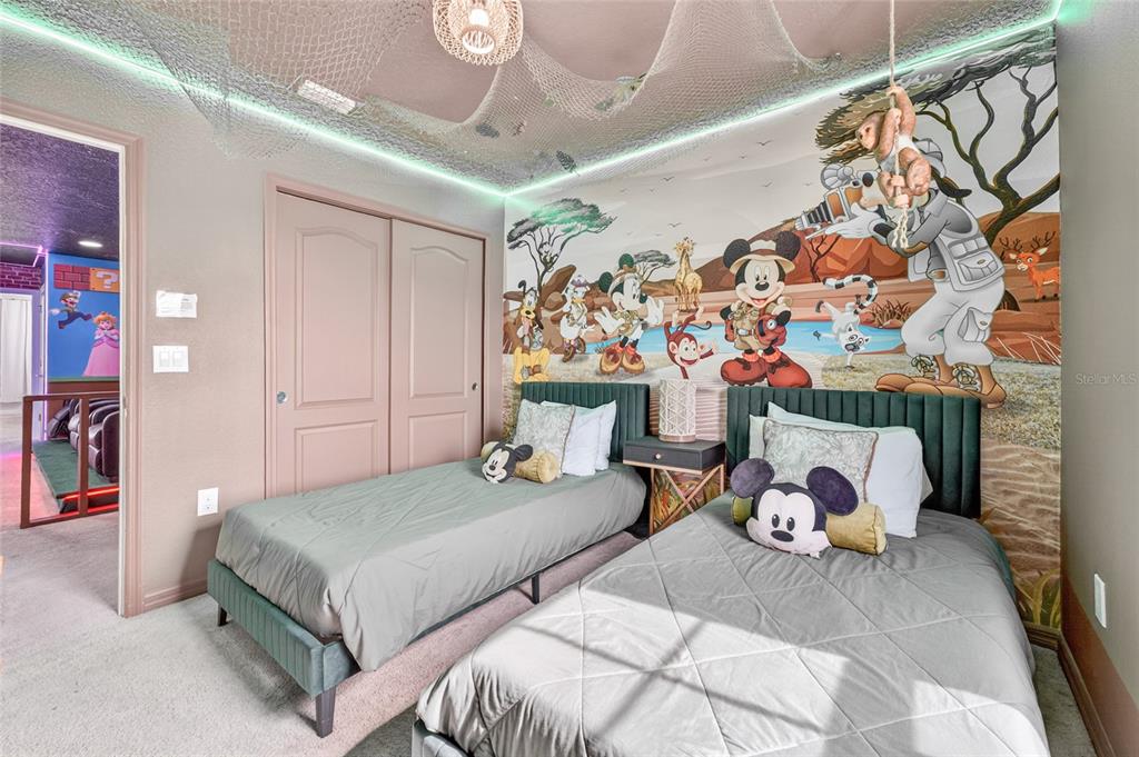 A bedroom features two twin beds, a Disney safari-themed mural, and a decorative ceiling net — 2417 DUBAI STREET, KISSIMMEE, FL