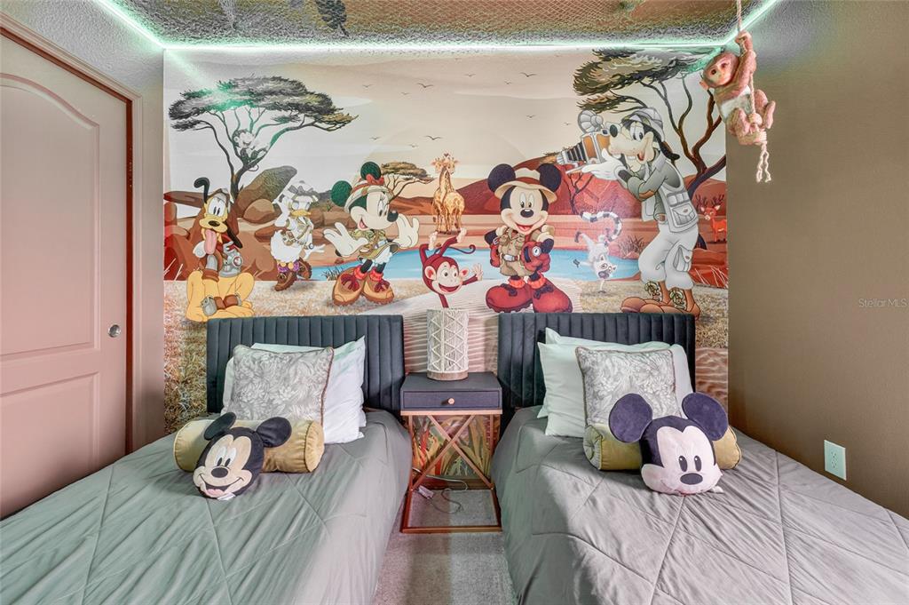 A bedroom features two twin beds with a Disney-themed safari mural on the back wall — 2417 DUBAI STREET, KISSIMMEE, FL