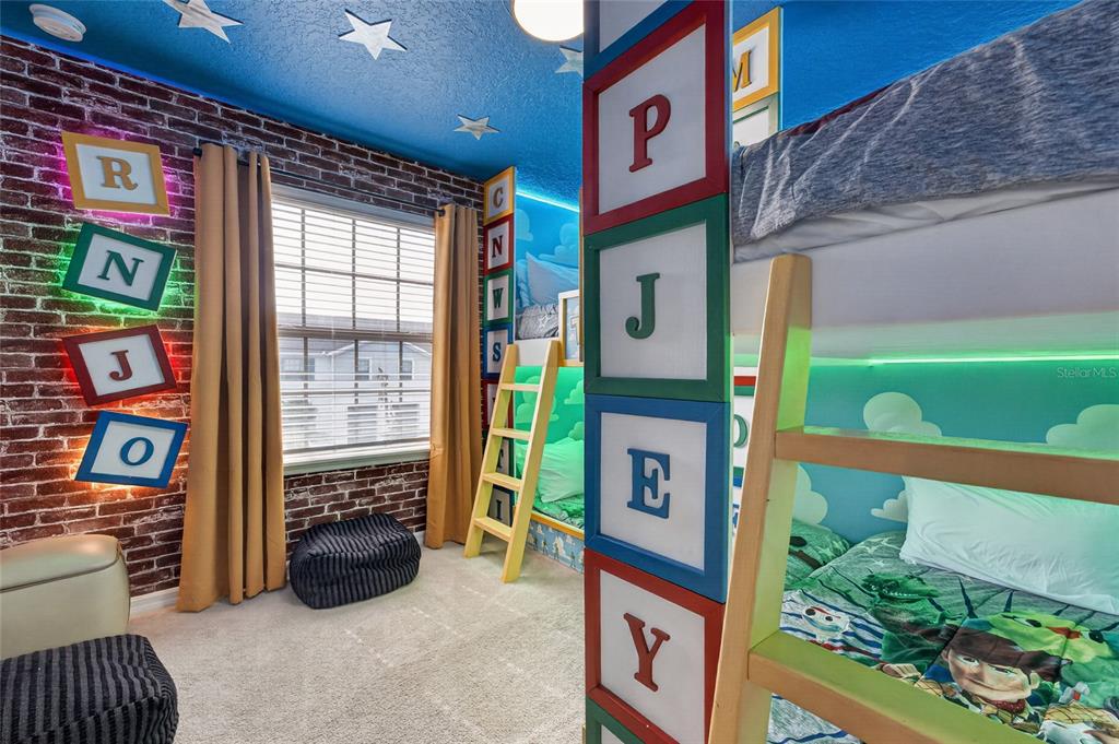 A themed bedroom features bunk beds, brick-patterned walls, and large block-style letters on the walls — 2417 DUBAI STREET, KISSIMMEE, FL