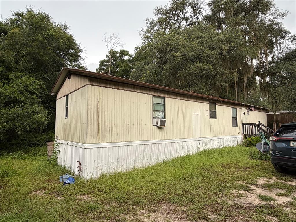 An exterior view of a single-wide mobile home with light-colored siding and a wooden deck — 12788 SE 102ND COURT, BELLEVIEW, FL