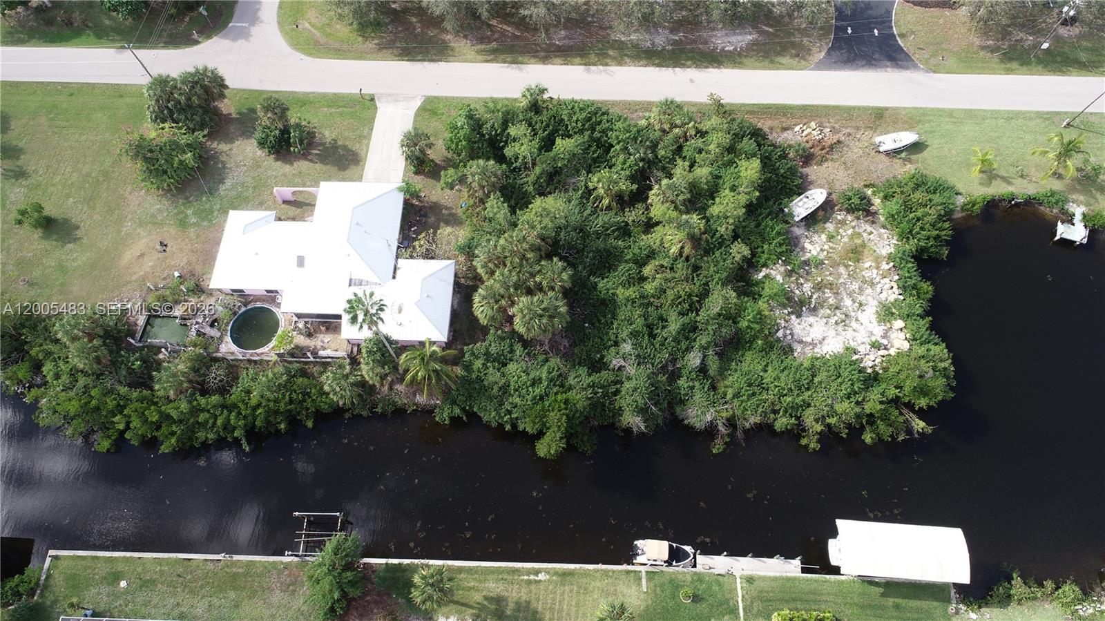 An aerial view shows a house with a pool next to a canal and vegetation — 4114 PALM, Punta Gorda FL 33950, PUNTA GORDA, FL