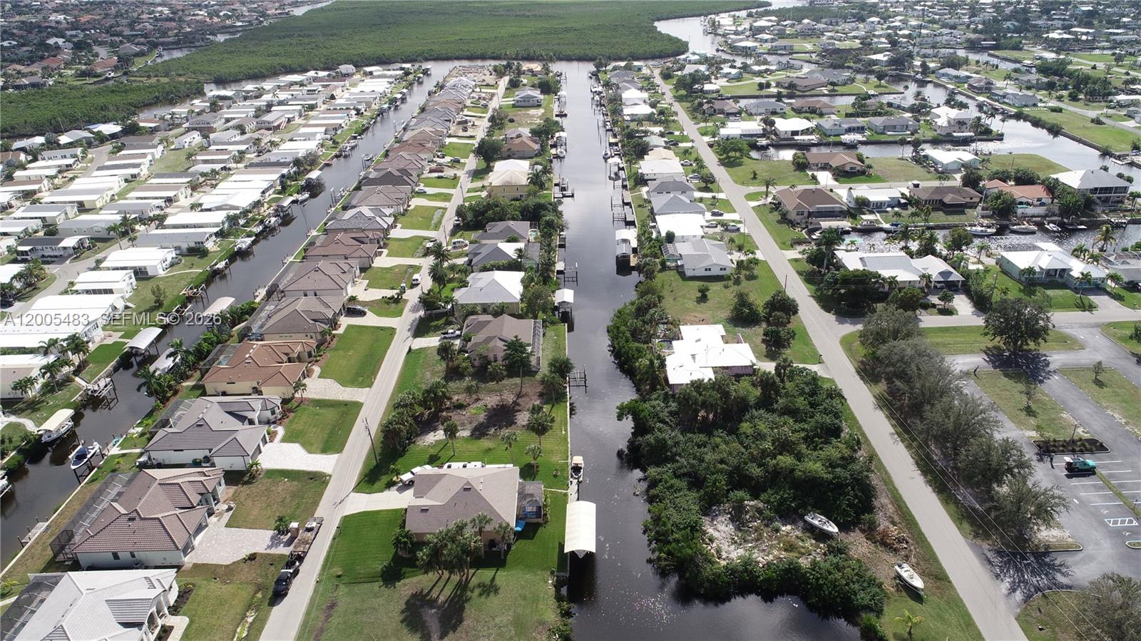 An aerial view shows a residential neighborhood with houses lining a central canal — 4114 PALM, Punta Gorda FL 33950, PUNTA GORDA, FL