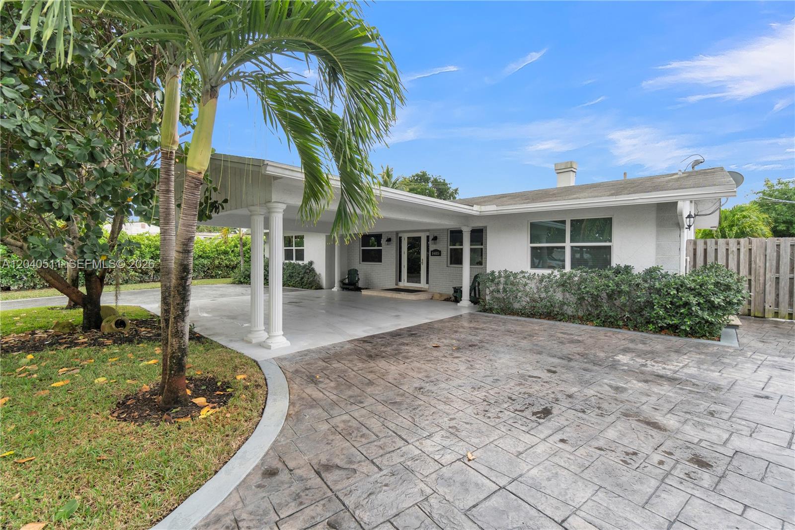 A white house features a covered carport with decorative columns and a stamped concrete driveway — 1405 SW 4th Ter, Pompano Beach FL 33060, POMPANO BEACH, FL