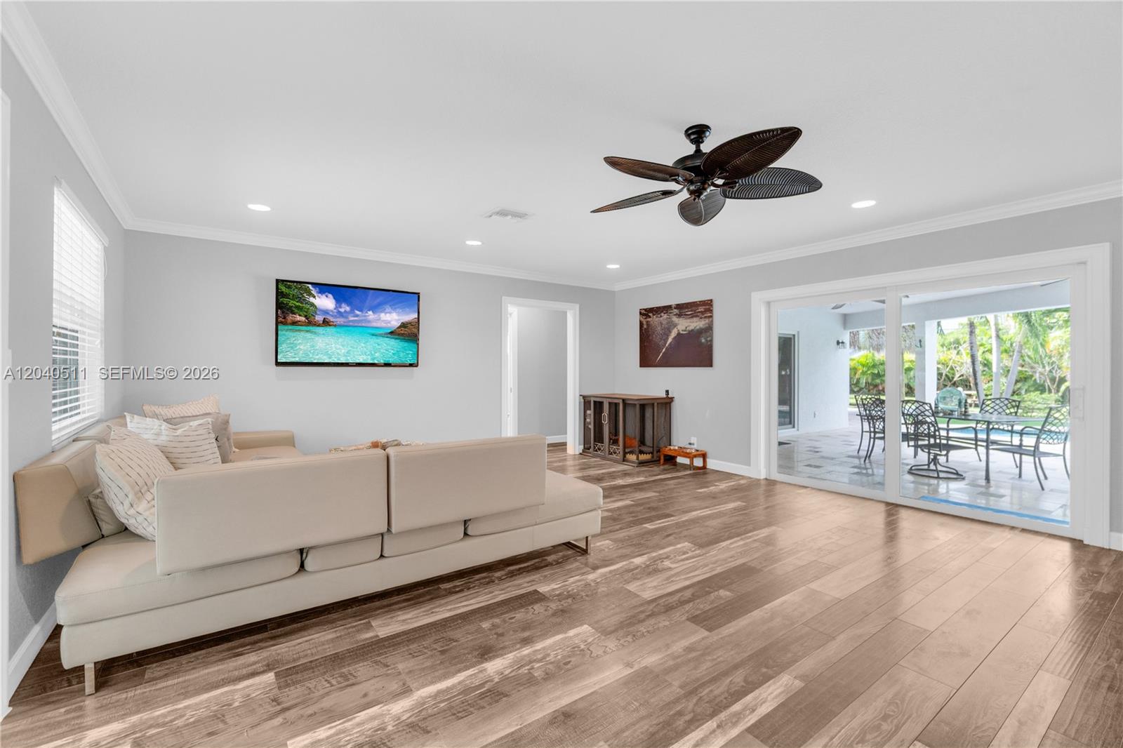 A living room features light gray walls, wood-look flooring, a sectional sofa, and sliding glass doors — 1405 SW 4th Ter, Pompano Beach FL 33060, POMPANO BEACH, FL
