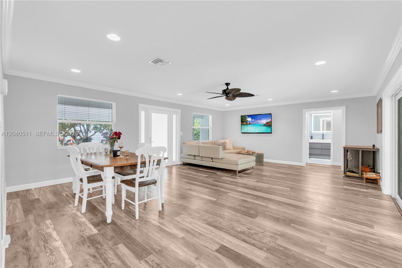 A dining area and living room feature light gray walls and wood-look flooring — 1405 SW 4th Ter, Pompano Beach FL 33060, POMPANO BEACH, FL