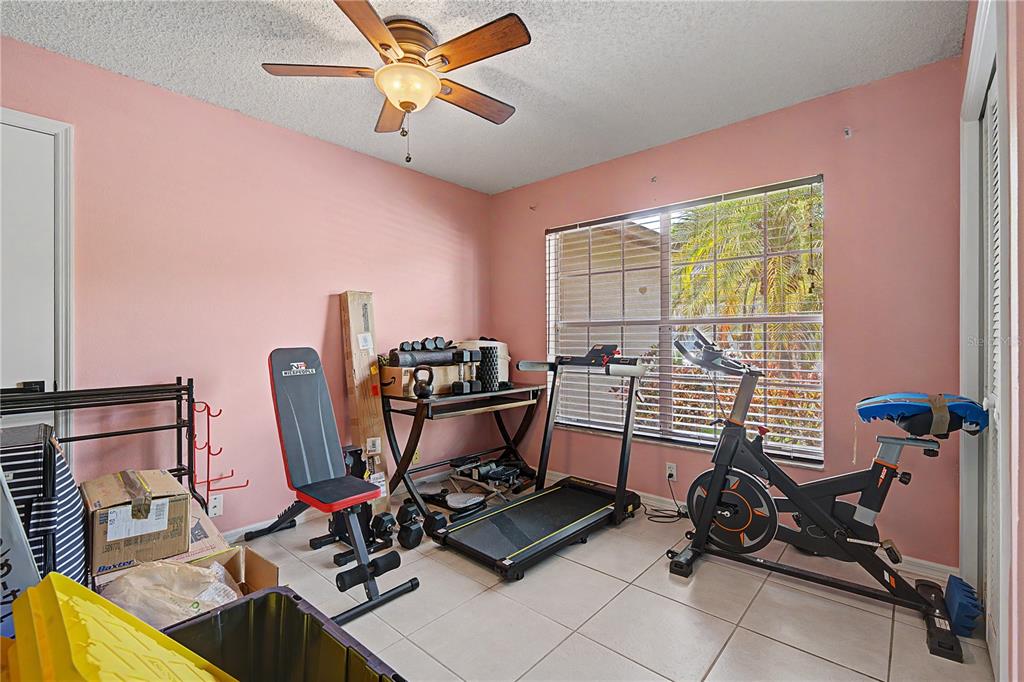 A home gym with pink walls, tile flooring, a ceiling fan, and various exercise equipment — 7201 FORESTEDGE COURT, NEW PORT RICHEY, FL