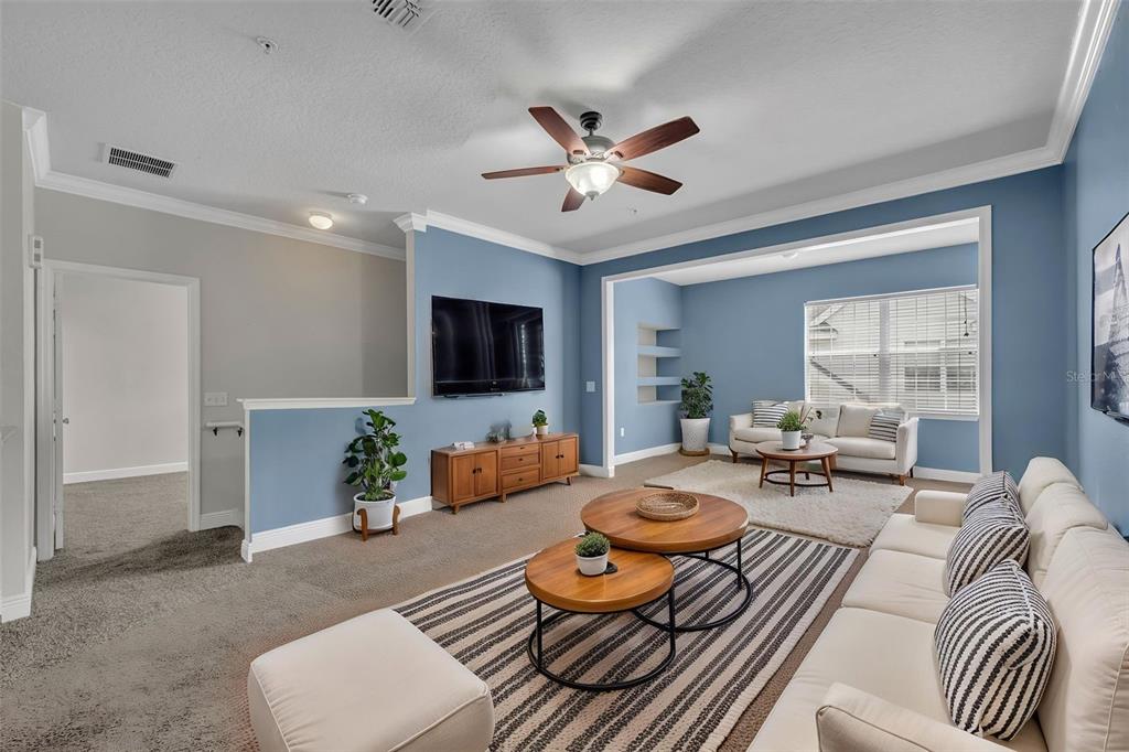 A living room with blue walls, a ceiling fan, two sofas, and two coffee tables — 200 SOUTHERN PECAN CIRCLE UNIT 206, WINTER GARDEN, FL